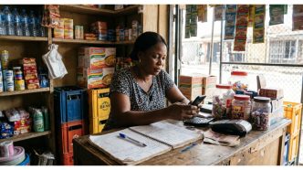 Nigerian retail seller reviewing insurance policy details on a phone